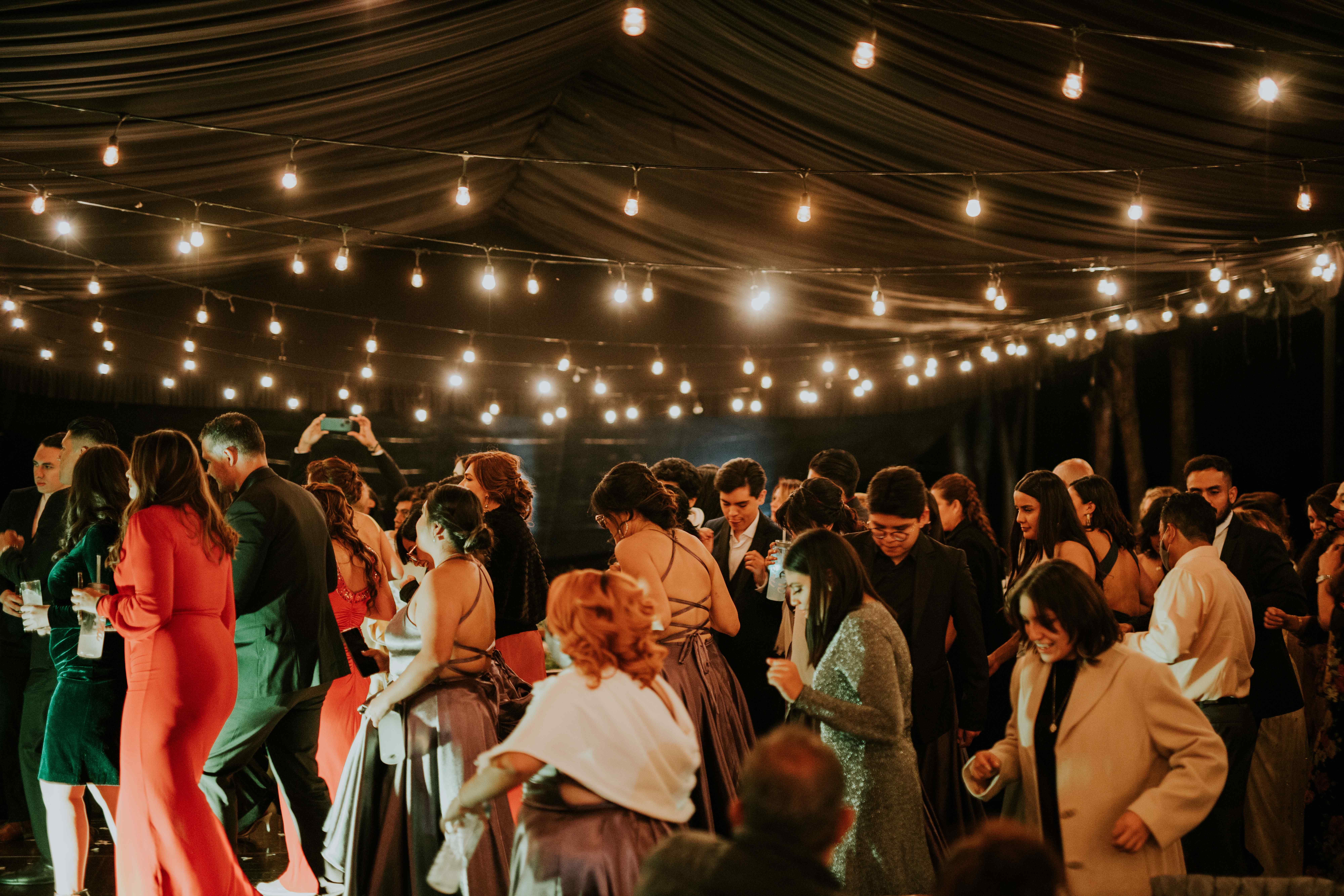 Multitud bailando bajo guirnaldas de luces en carpa