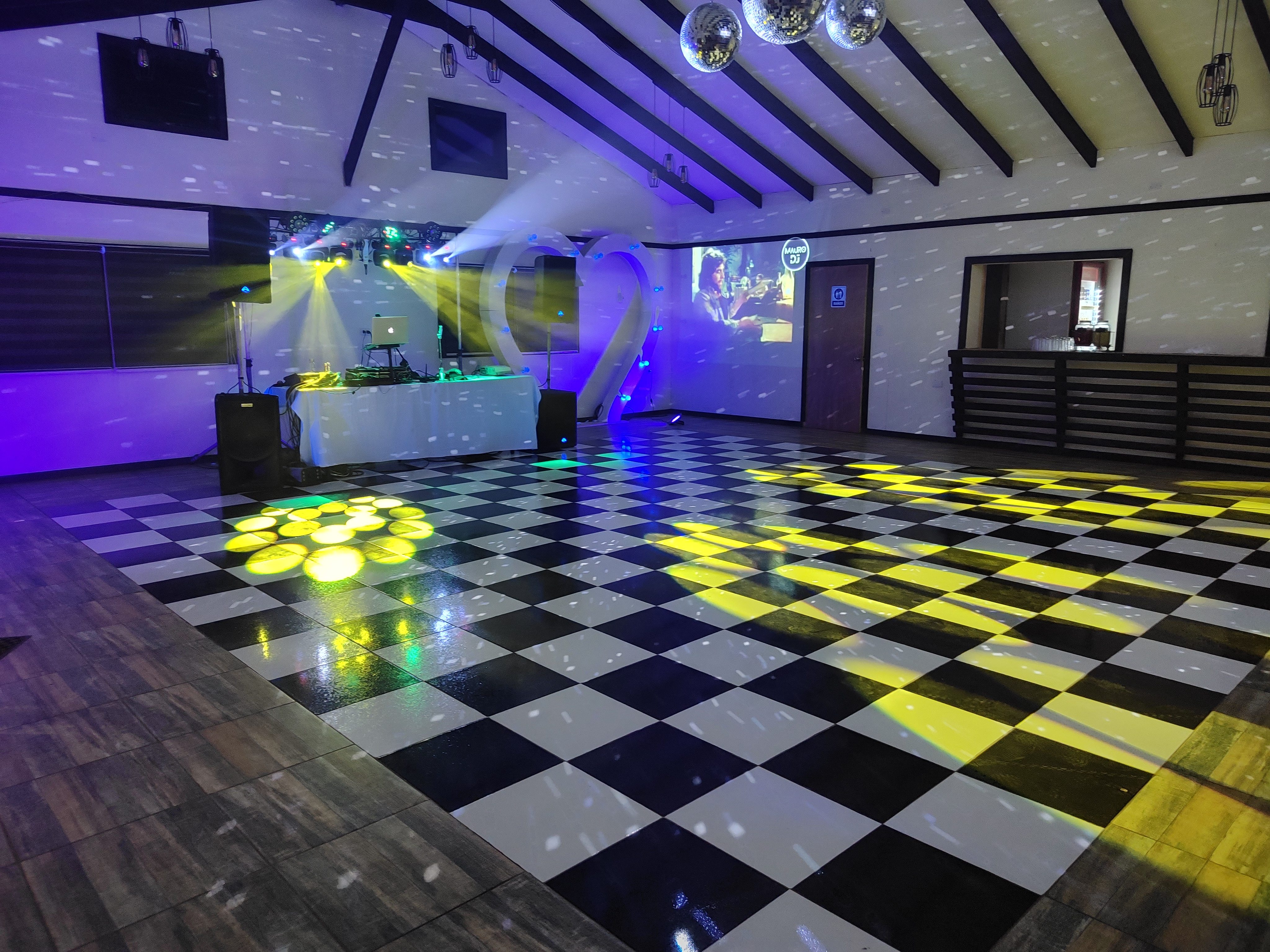Pista de baile ajedrezada con luces robóticas y logo MauroDJ