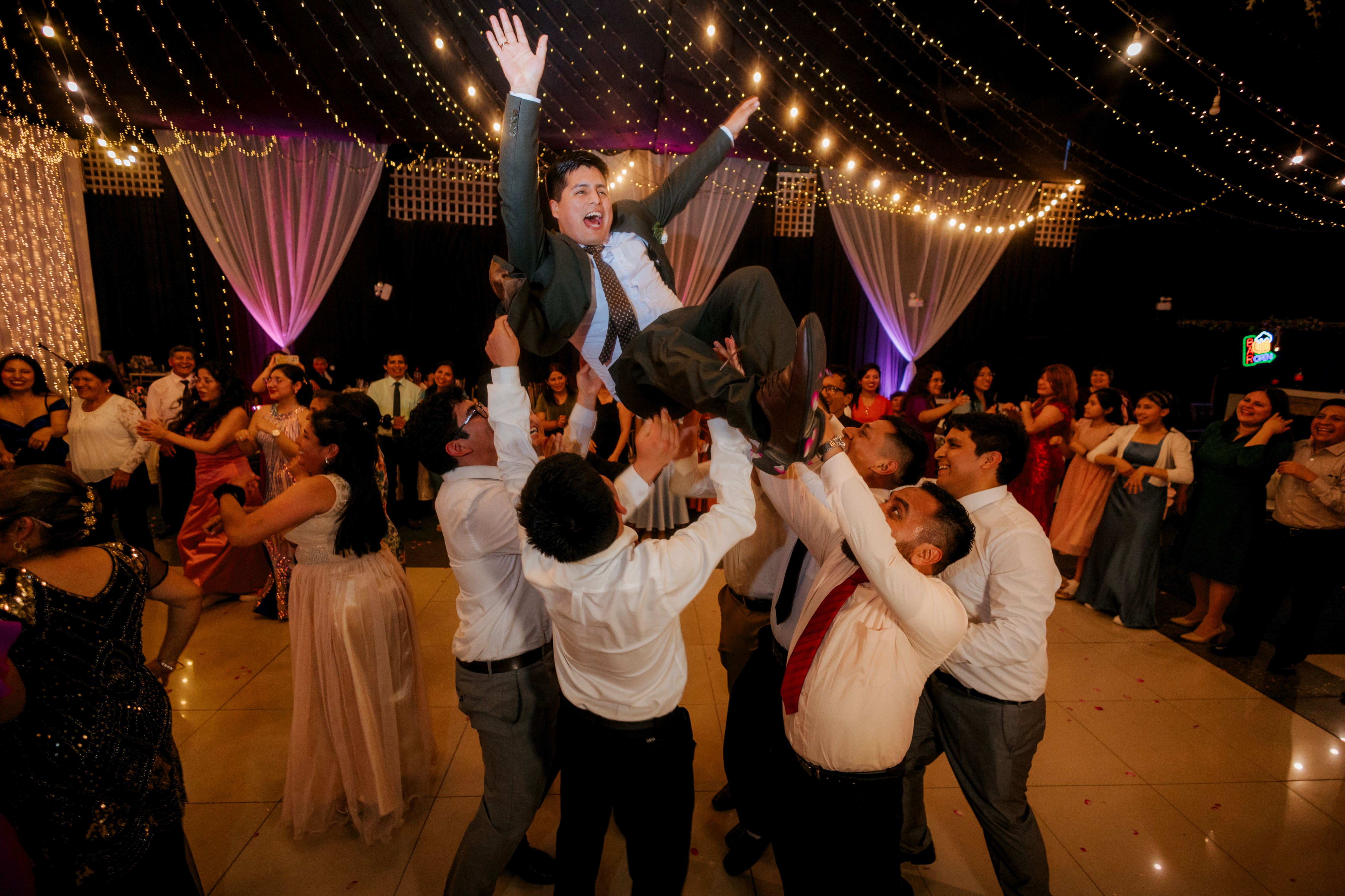 Invitado siendo levantado por el grupo en plena fiesta