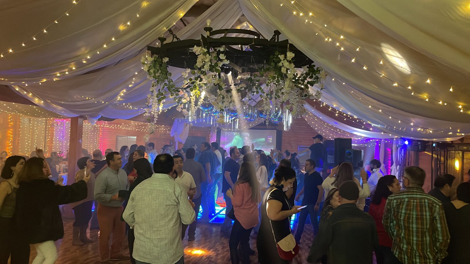 Pista repleta de invitados bailando bajo guirnaldas y flores